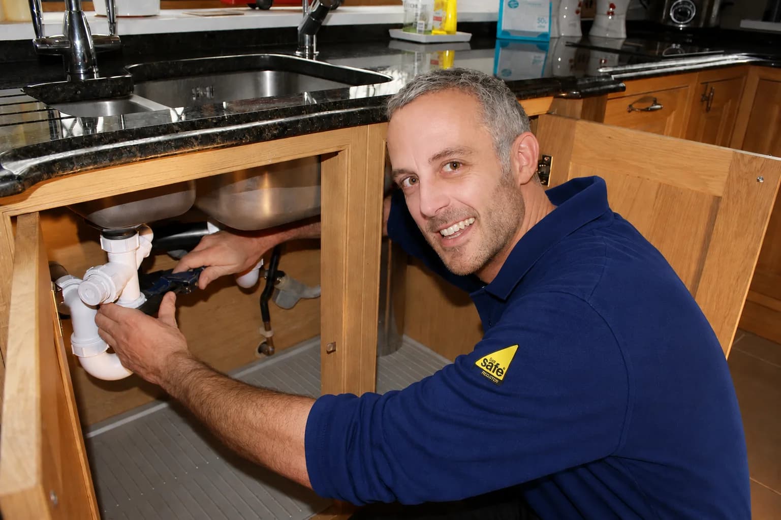 Our engineer fixing the waste pipe under a kitchen sink